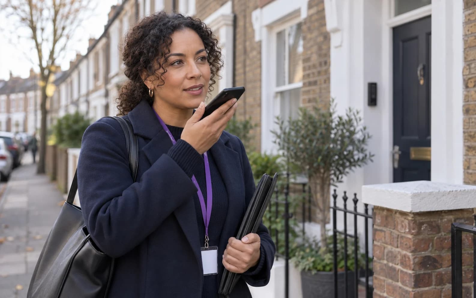 A council housing officer recording a voice note on a phone after a property visit